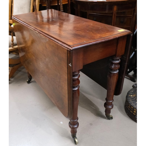 869 - A heavy 19th century drop leaf table of rounded rectangular form with turned legs, brass castors, le... 