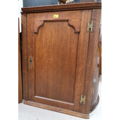 937 - An 18th Century oak corner cupboard with raised arch panel doors.