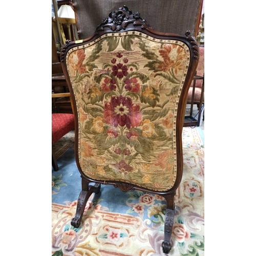 968 - A Victorian walnut framed fire screen with carved decoration and needlework panel.