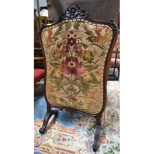 968 - A Victorian walnut framed fire screen with carved decoration and needlework panel.