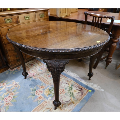 918 - A Georgian style circular wind out dining table, one spare leaf on ball and claw feet