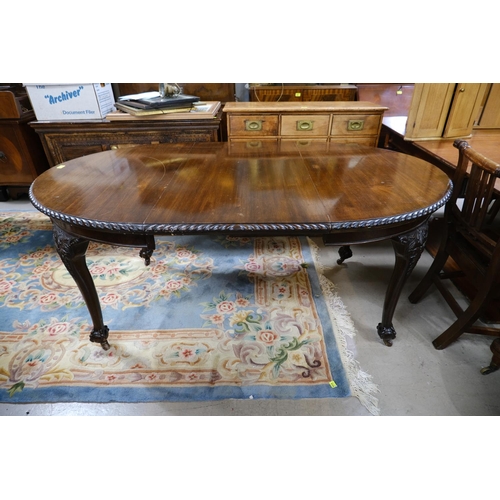 918 - A Georgian style circular wind out dining table, one spare leaf on ball and claw feet