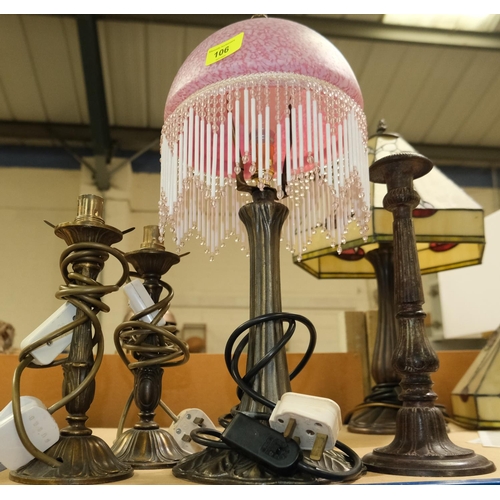 106 - An Art Nouveau style lamp base with pink glass and beaded fringe shade, 2 similar lamp bases and a c... 