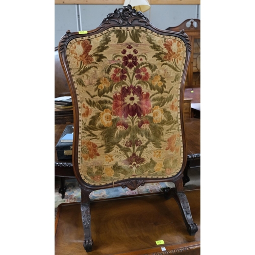 968 - A Victorian walnut framed fire screen with carved decoration and needlework panel.