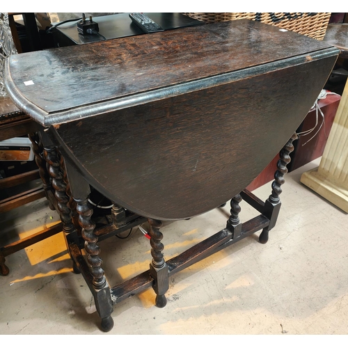 926 - An oval oak drop leaf dining table on barley twist legs