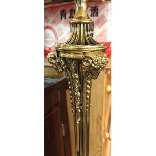 975 - An ornate brass standard lamp with ram mask mounts and trefoil base.