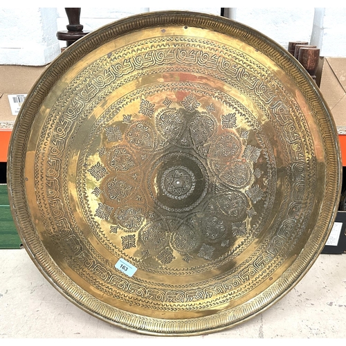 163 - A Middle Eastern circular brass tray table with folding stand inlaid with mother of pearl.