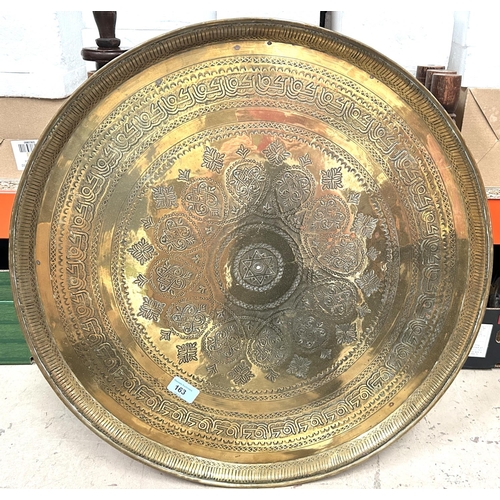 163 - A Middle Eastern circular brass tray table with folding stand inlaid with mother of pearl.