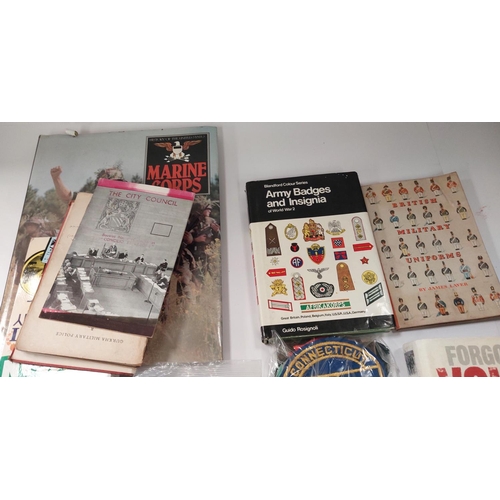 255 - A collection of military cap and other badges, some cloth examples and hard back military books etc