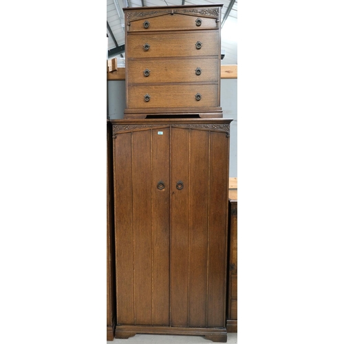 874 - An oak carved two piece bedroom set comprising oak chest of four drawers and a two door wardrobe wit... 