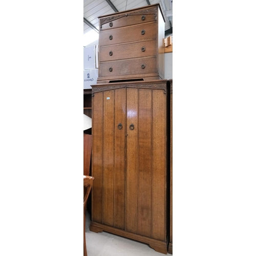 875 - An carved oak two-piece bedroom suite comprising a four-height chest of drawers and a two-door wardr... 