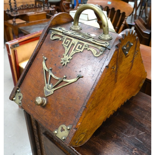 896 - An Asthetic movement oak coal scuttle with brass bindings and decoration, with shoval