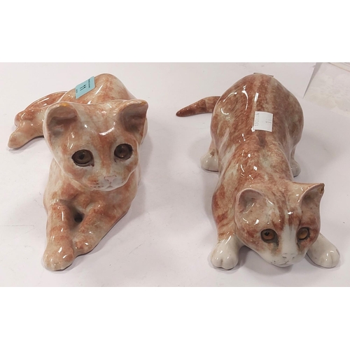 11 - A Winstanley cat, glass eyes, lying down, length 26cm, signed; another similar with glass eyes, sign... 