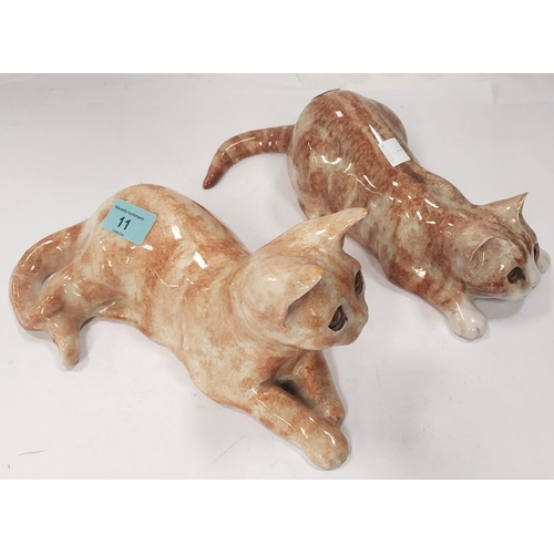 11 - A Winstanley cat, glass eyes, lying down, length 26cm, signed; another similar with glass eyes, sign... 