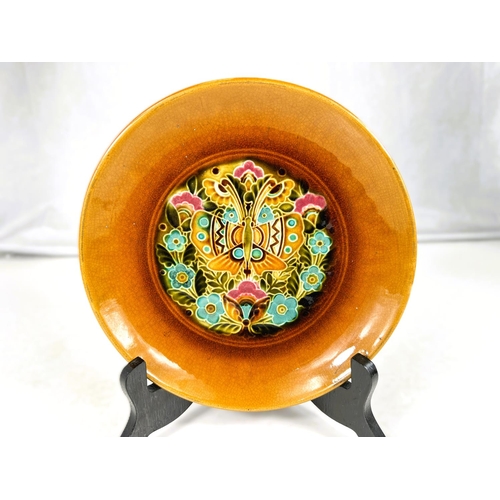551 - Linthorpe Art Pottery: A shallow dish with multicoloured stylised floral central panel with toffee c... 