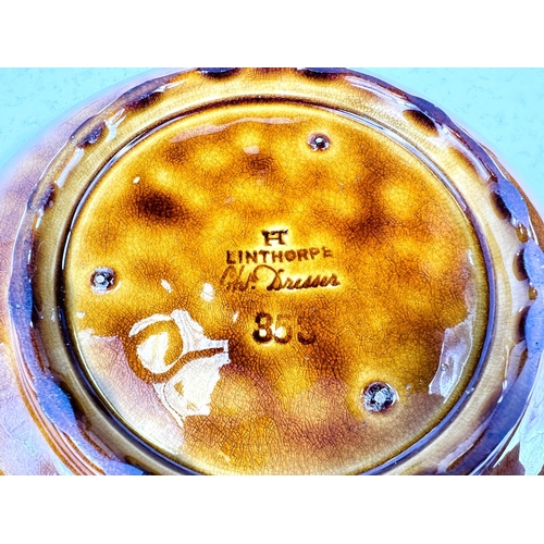 551 - Linthorpe Art Pottery: A shallow dish with multicoloured stylised floral central panel with toffee c... 