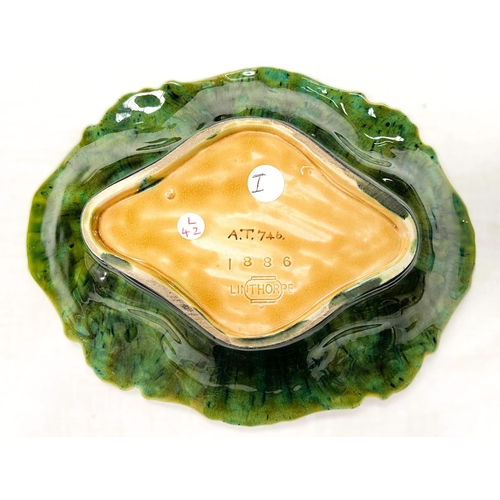 555A - Linthorpe Art Pottery: An oval dish with relief flower and scroll border under yellow/green glaze. I... 