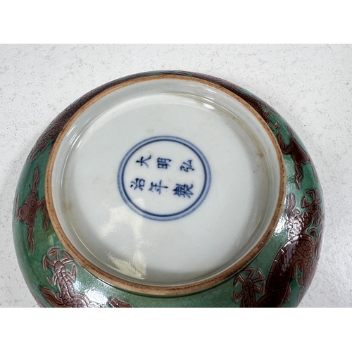 576 - A Chinese green ground glazed dish with central incised dragon in brown glaze with six character mar... 