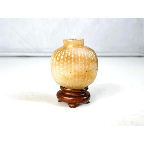 577B - A Chinese jade coloured hard stone snuff bottle with scale light carving to body with small wooden s... 