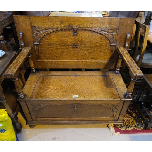 882 - A carved oak Monks Bench with hinged storage compartment.