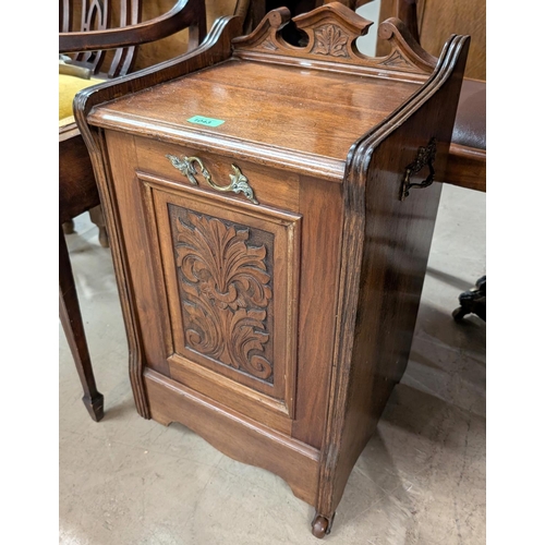 1043 - An Edwardian carved oak fall front coal scuttle with carved panel and brass fittings.