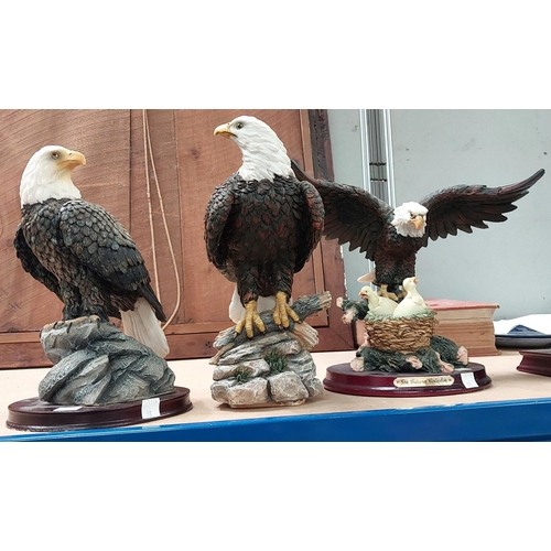 98 - Three resin figures of eagles including one with eaglets; four modern resin owl figures.