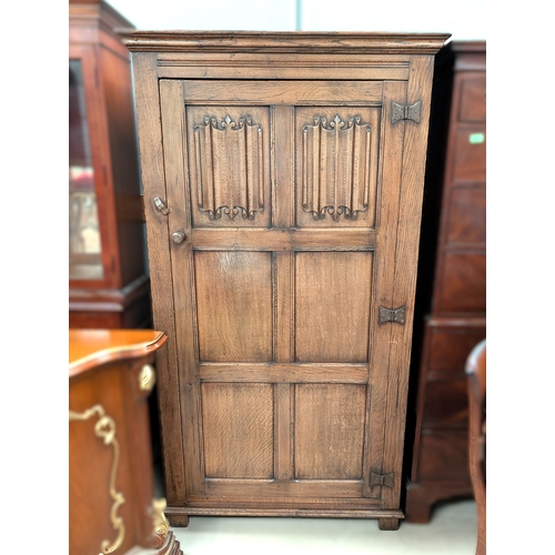 1061 - A golden oak single door wardrobe with panel door with carved linen fold panels.91 x 57 x 178cm heig... 