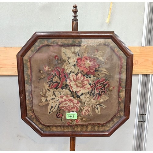 1042 - A 19th century mahogany pole screen with floral tapestry picture in canted glazed square.