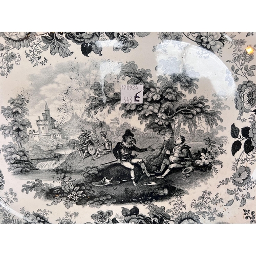 522 - A rounded rectangular meat platter decorated in underglaze black with a rural scene taken from Don Q... 