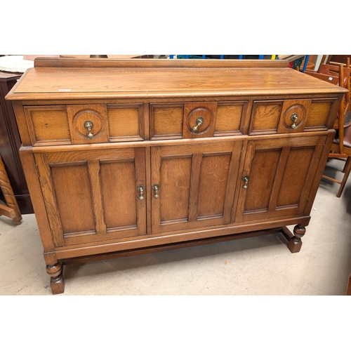 935 - A golden oak sideboard with three cupboards and three drawers below.