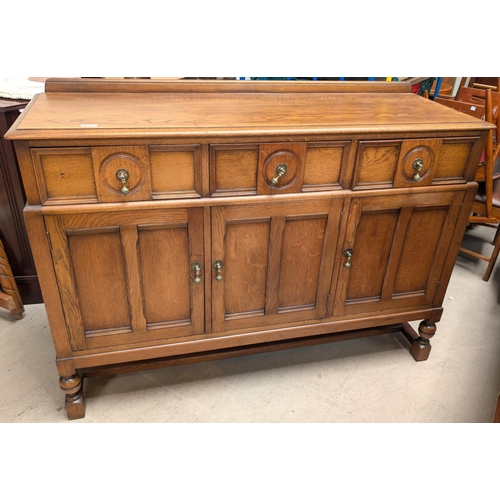 935 - A golden oak sideboard with three cupboards and three drawers below.