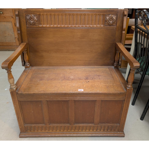 1006 - A golden oak Monks Bench with carved back and hinged seat.