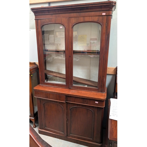 1023 - A 19th century mahogany full height bookcase with panelled doors and two frieze drawers below, glaze... 