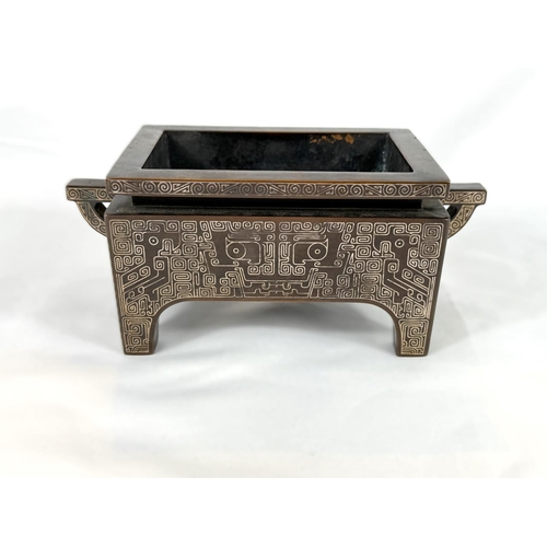 415B - A Chinese bronze censer with inlaid white metal decoration to the body and base, of rectangular form... 