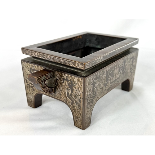 415B - A Chinese bronze censer with inlaid white metal decoration to the body and base, of rectangular form... 