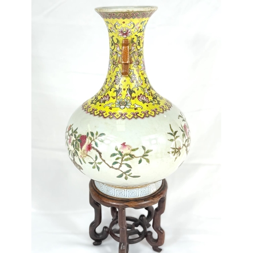 417A - A Chinese squat baluster vase on stand with yellow ground neck and polychrome decoration, of fruits ... 