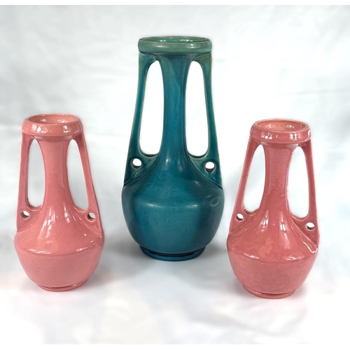 469 - Christopher Dresser for Bretby, a pair of bulbous pink vases with elongated necks and side handles, ... 