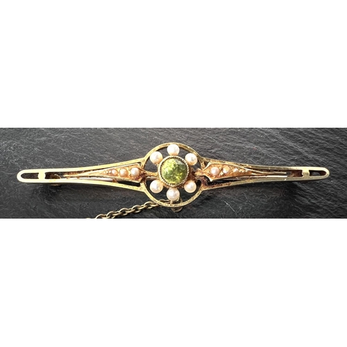 685 - An Edwardian peridot and pearl bar brooch, stamped 15ct, 4.0gms in original box.