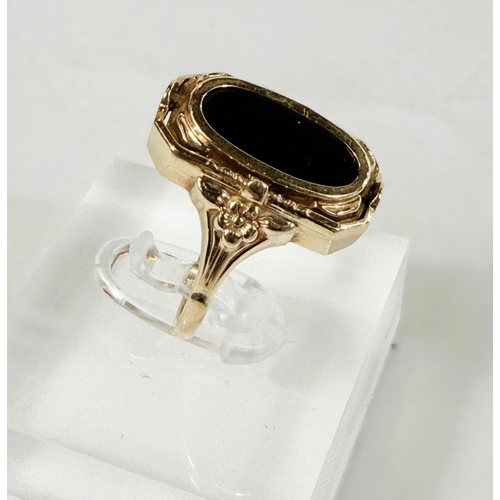 705 - A yellow metal ring set with a swivel alternating cameo and obsidian coloured stone, unmarked, 4.4gm... 