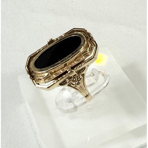 705 - A yellow metal ring set with a swivel alternating cameo and obsidian coloured stone, unmarked, 4.4gm... 