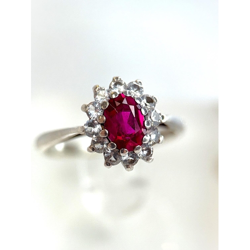 724 - A white metal dress ring set with diamonds and central ruby, 2.2gm, size M-N