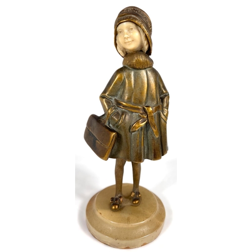 818 - An Art Deco gilt bronze figure of a young girl in coat holding a bag, with carved ivory face, on mot... 