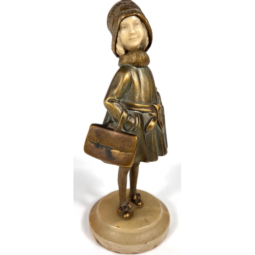 818 - An Art Deco gilt bronze figure of a young girl in coat holding a bag, with carved ivory face, on mot... 