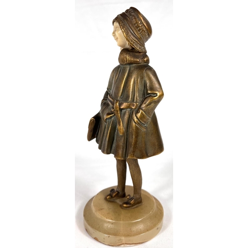 818 - An Art Deco gilt bronze figure of a young girl in coat holding a bag, with carved ivory face, on mot... 