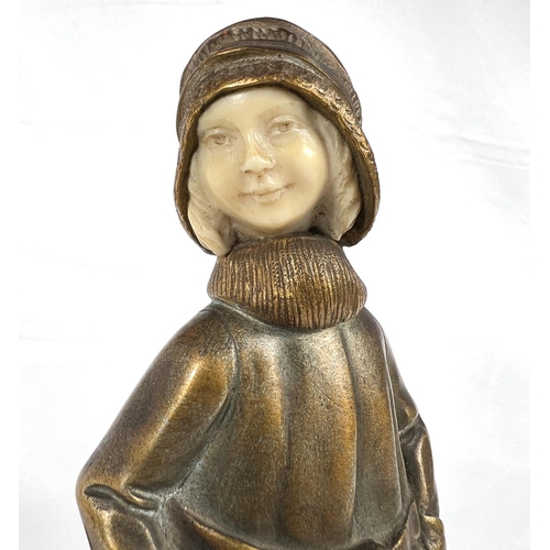 818 - An Art Deco gilt bronze figure of a young girl in coat holding a bag, with carved ivory face, on mot... 