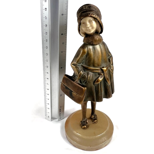 818 - An Art Deco gilt bronze figure of a young girl in coat holding a bag, with carved ivory face, on mot... 