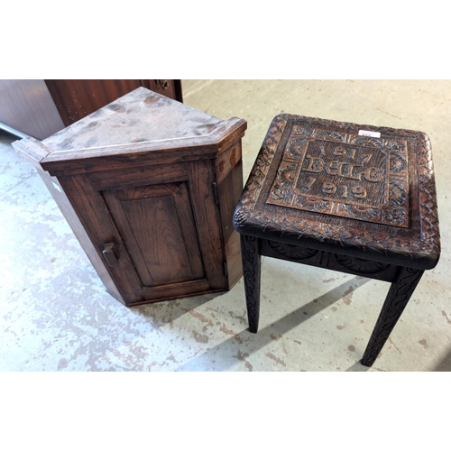 875 - A carved oak stool commemorating WWI and a small oak corner cupboard.