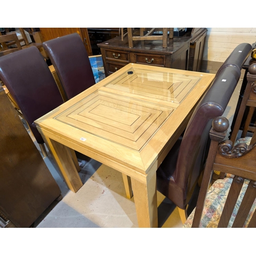 897 - A light oak extending dining table with single leaf and four high back dining chairs.