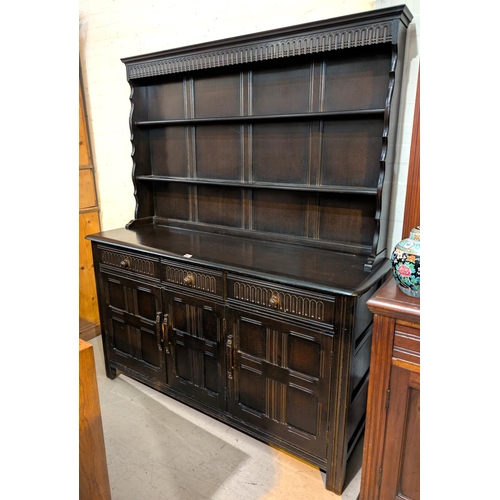 900 - An Ercol Welsh Dresser with panel 3 doors, 3 drawers and three height rack above, length 150 cm.