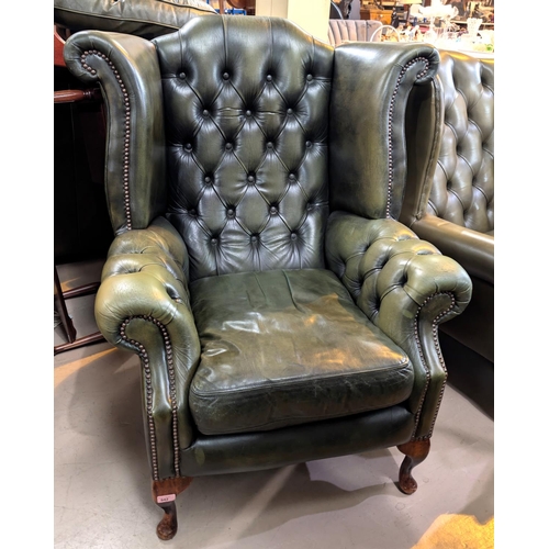 942 - An antique green high wing back chesterfield chair with button back and arms